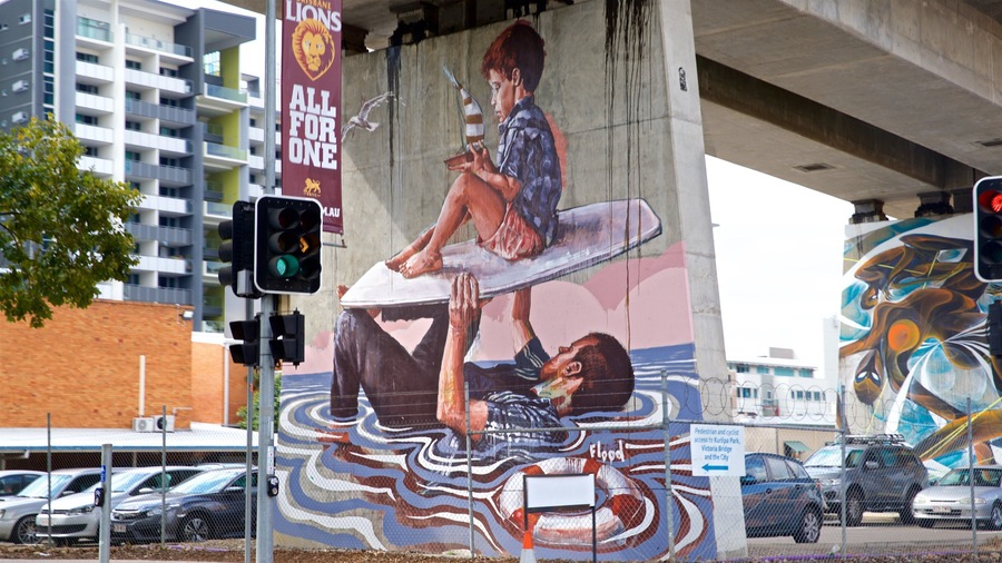 A mural on a concrete wall depicting a person surfing and another person lying on the ground.