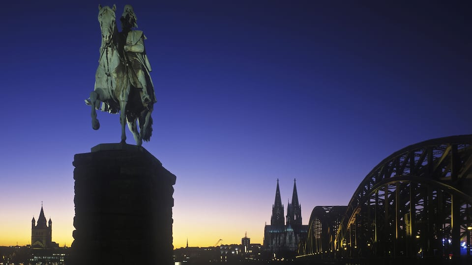View from Deutz Gross St Martin church equestrian statue of Kaiser Wilhelm I of Prussia Cologne Cathedral and Hohenzollernbruecke bridge blue hour evening illuminated Cologne North Rhine_Westphalia