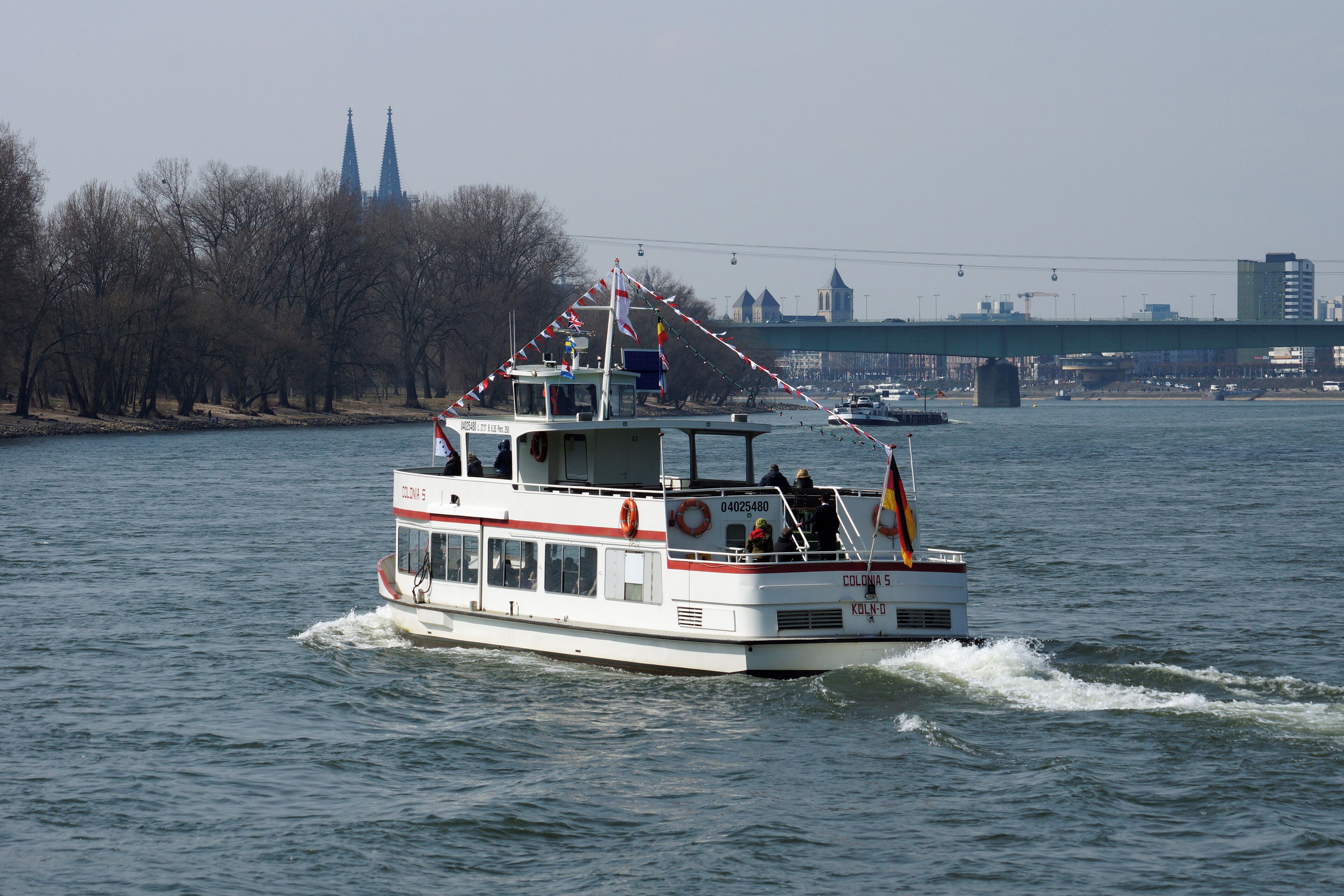 A white boat with red and white stripes on a river.