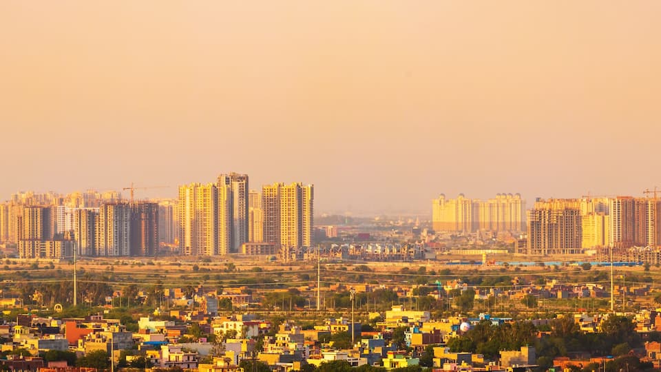 A cityscape with numerous high-rise buildings and construction cranes, indicating ongoing development.