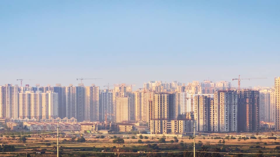 A cityscape with numerous high-rise buildings, construction cranes, and a clear sky.