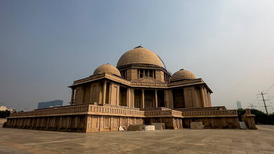 A large, historic building with a central dome and smaller domes on either side, surrounded by a spacious courtyard.