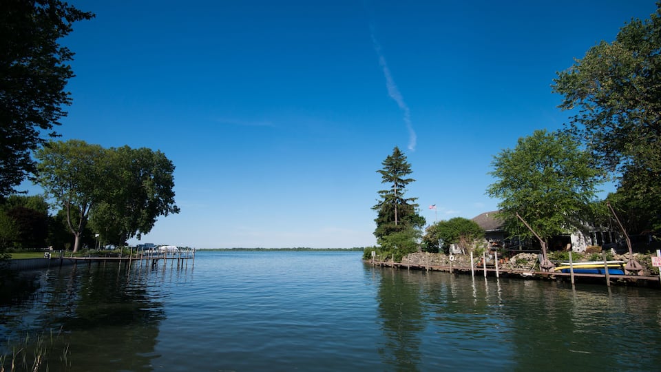 A calm lake with docks, trees, and a clear blue sky.
