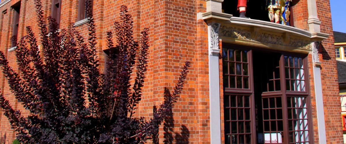 A brick building with a clock tower, a weather vane, and a statue of a man with a flag.
