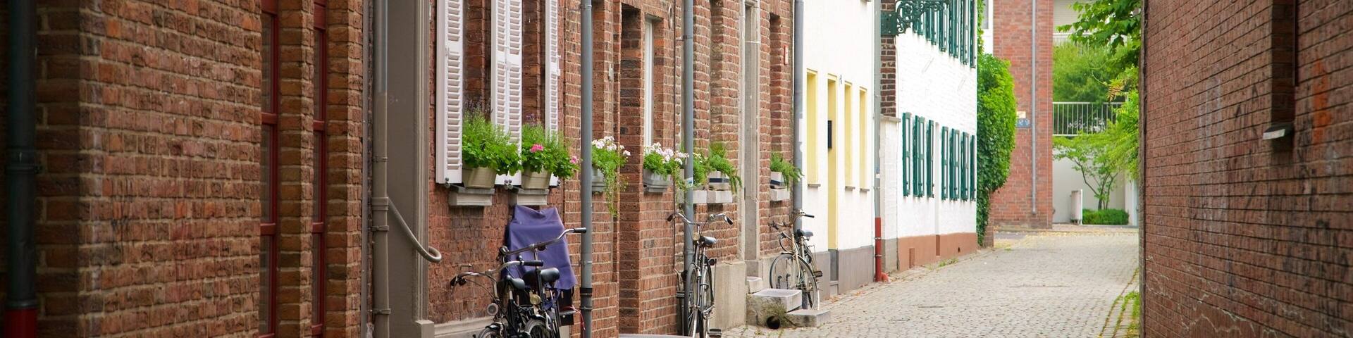 A cobblestone street lined with brick buildings, some with shutters and flower boxes.