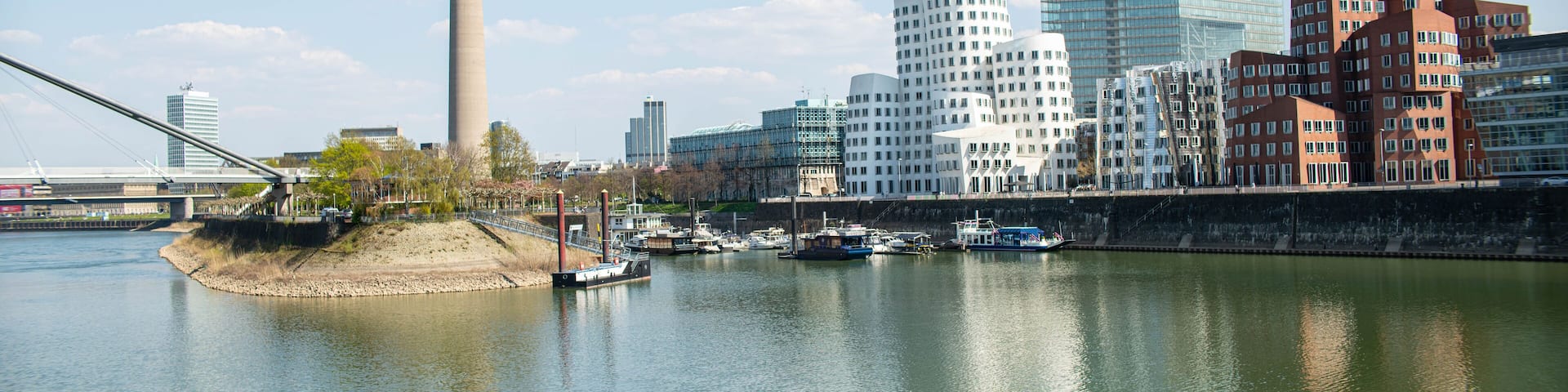 A river with boats, a tower, and modern buildings.