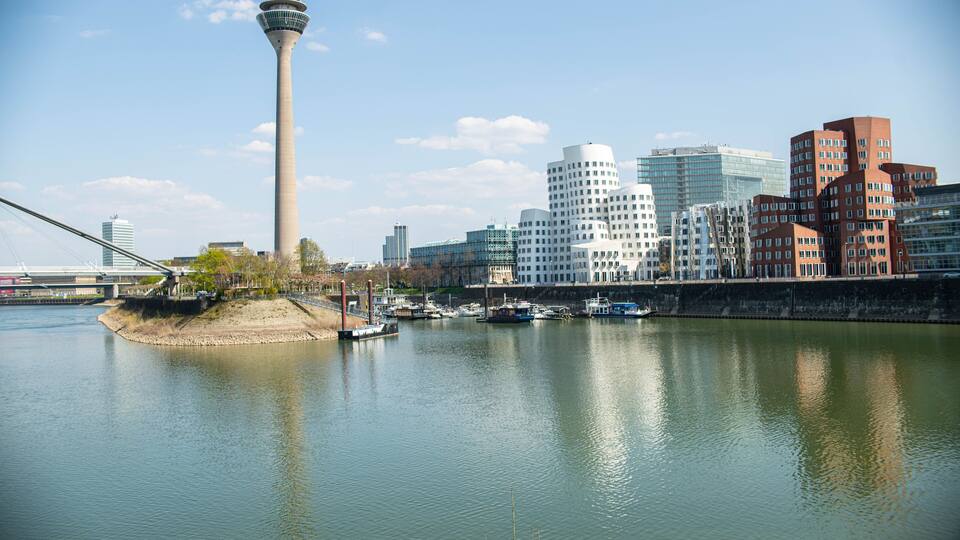 Un río con barcos, una torre y edificios modernos.