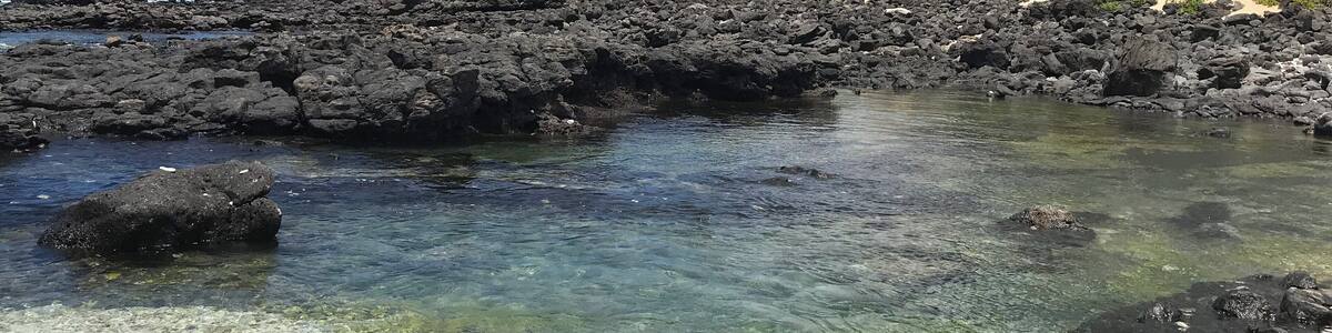Un littoral rocheux aux eaux cristallines, une montagne et une végétation luxuriante.