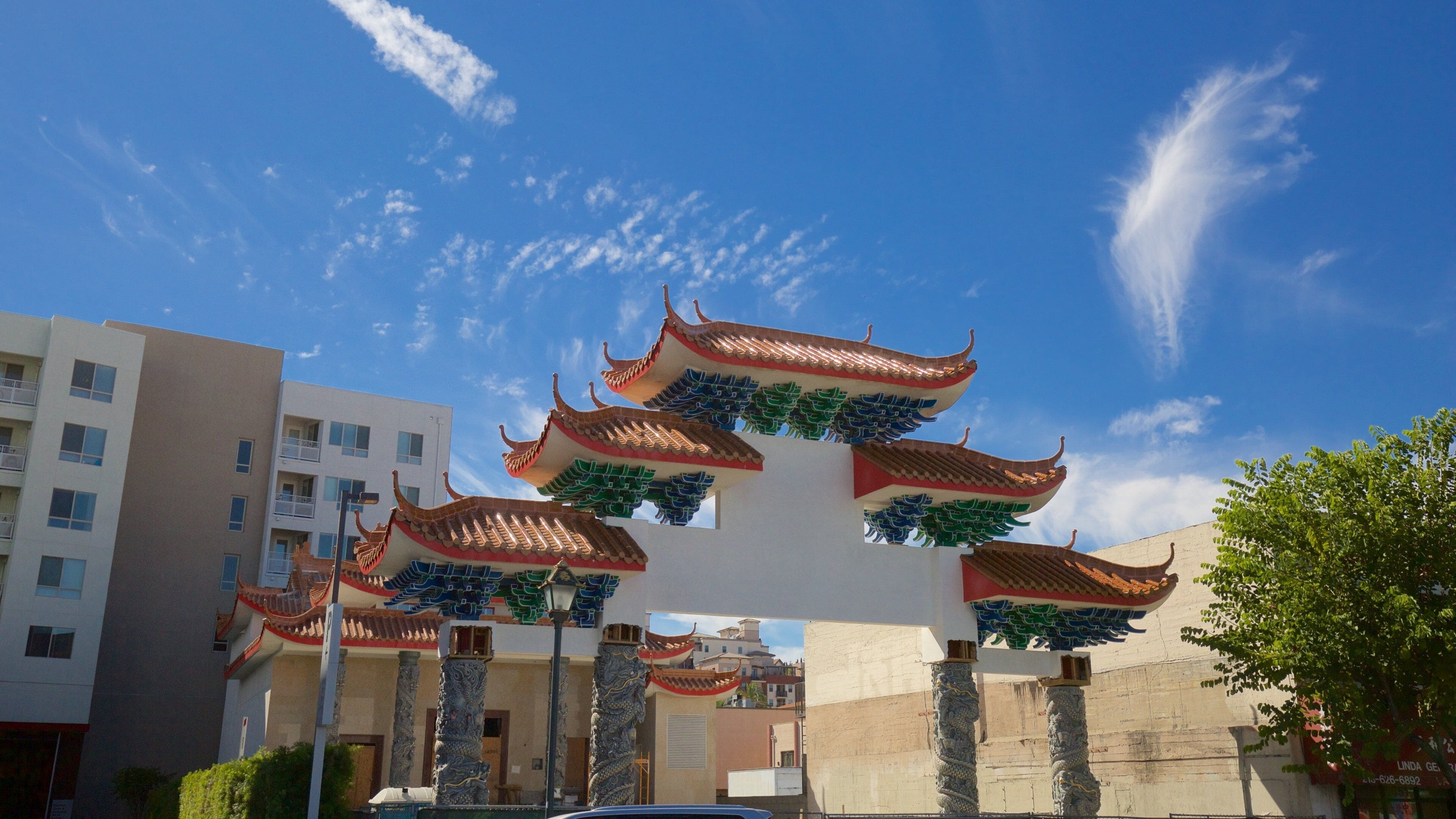 Uma pagoda chinesa tradicional com telhados ornamentados e esculturas de dragões, com um cenário de edifícios modernos e um céu azul límpido.