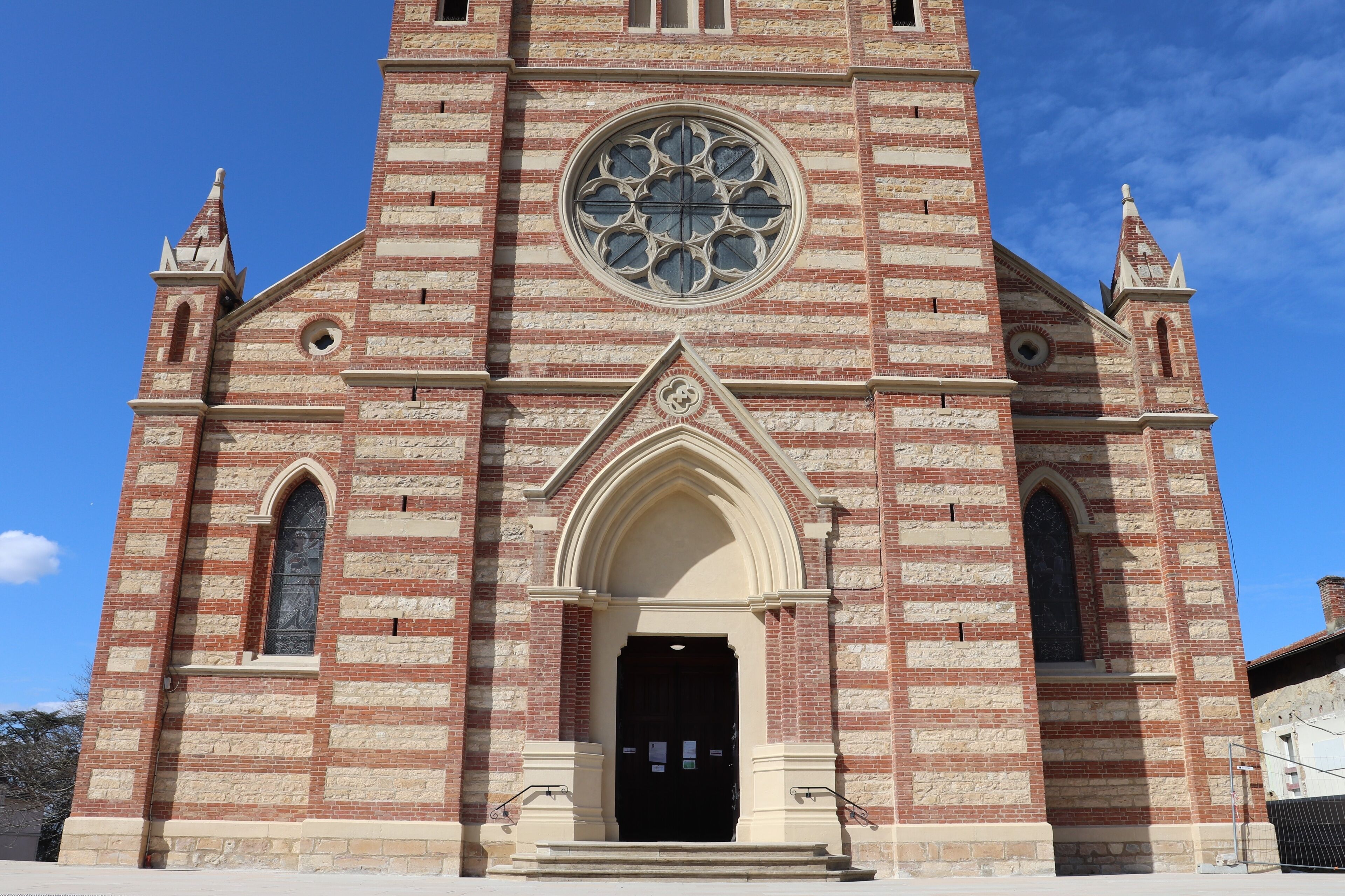 A large brick church with a prominent circular stained glass window and a tall bell tower.