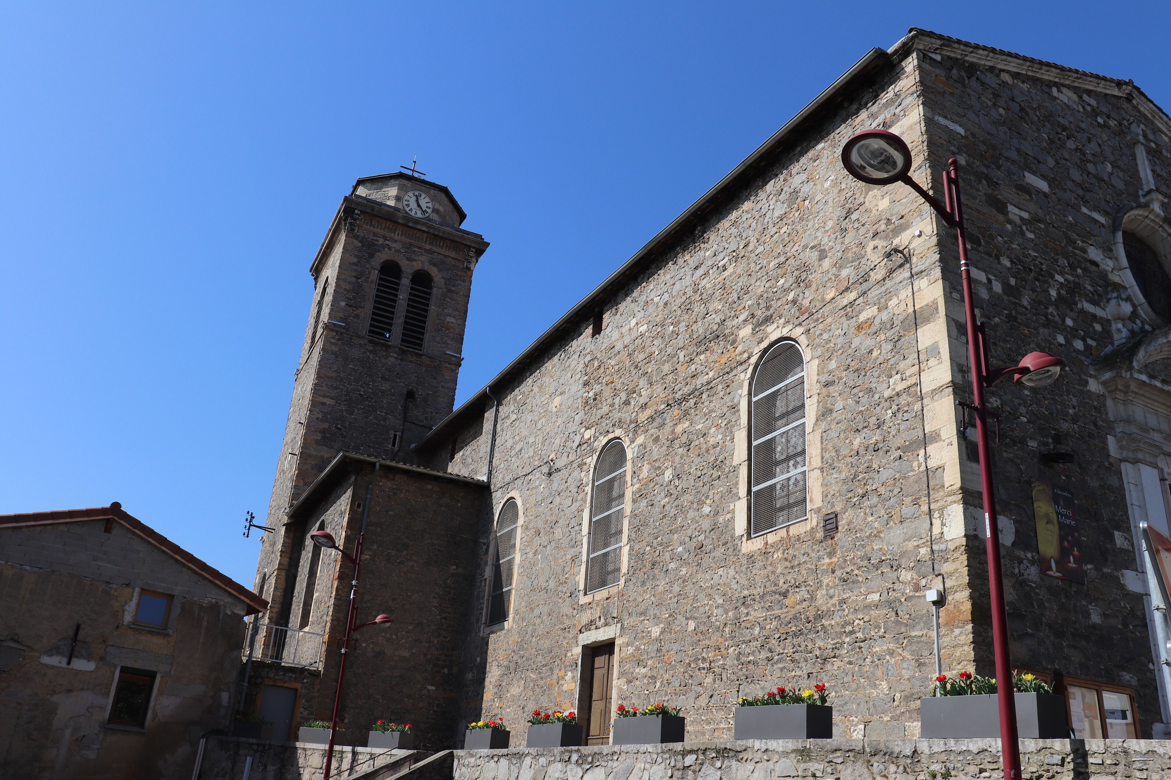A historic stone building with a clock tower, arched windows, and flower boxes.