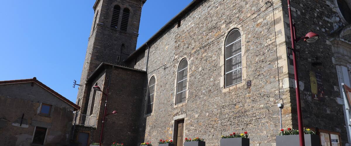 A historic stone building with a clock tower, arched windows, and flower boxes.