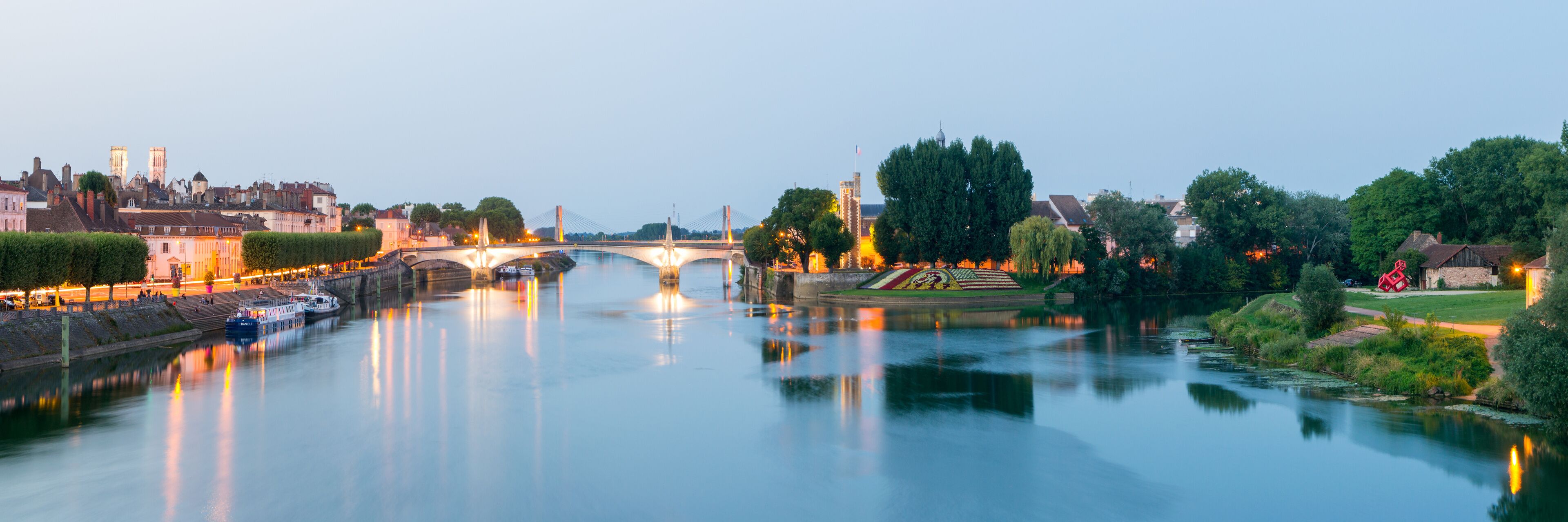 Un río con un puente, edificios y árboles.