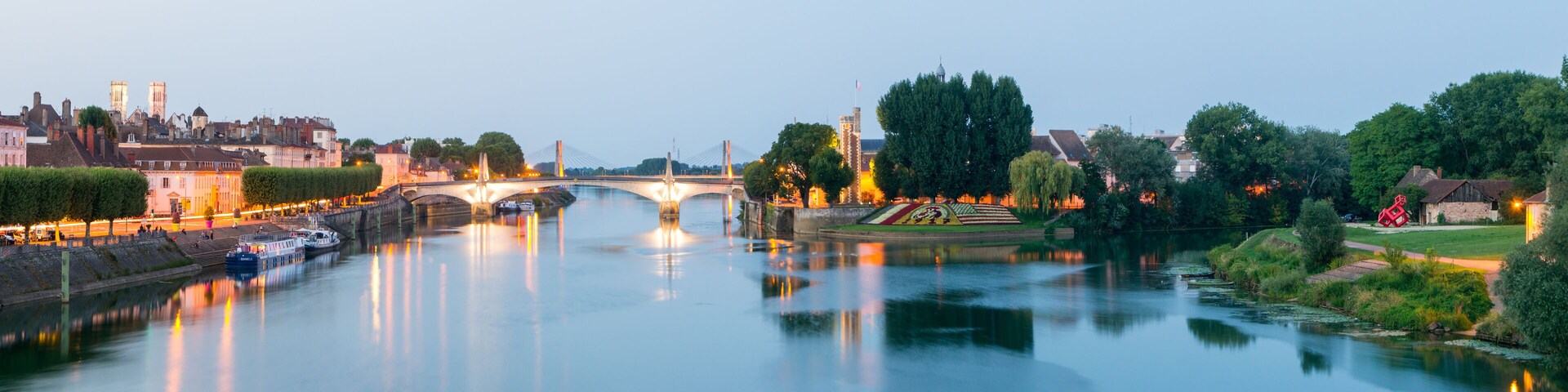 Un río con un puente, edificios y árboles.
