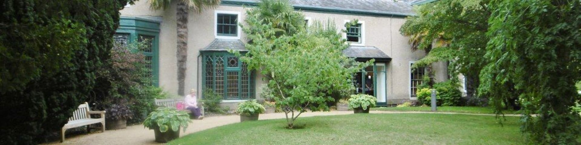 Uma casa com um gramado bem cuidado, um caminho e um banco.