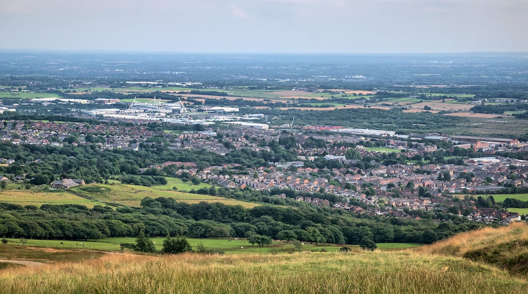 A panoramic view of a town with a mix of residential areas, green fields, and a large stadium.