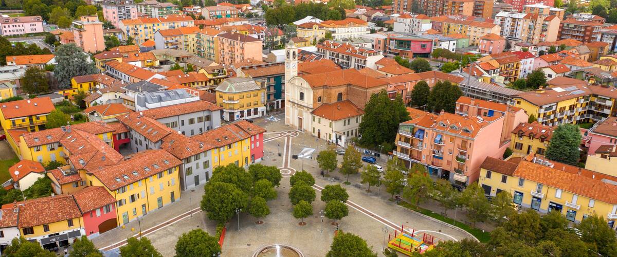 An aerial view of a colorful urban area with a central square, surrounded by multi-story buildings with red-tiled roofs.