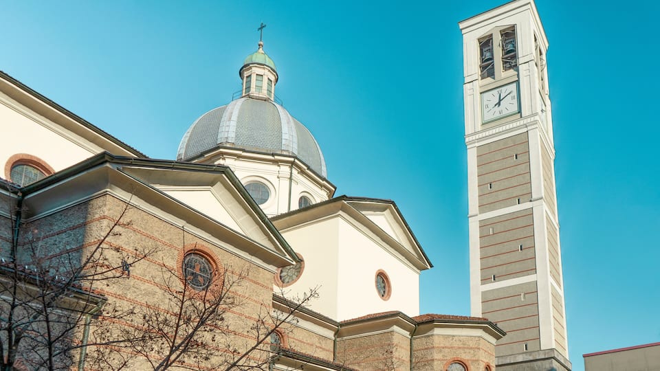 A church with a dome and a clock tower against a clear blue sky.