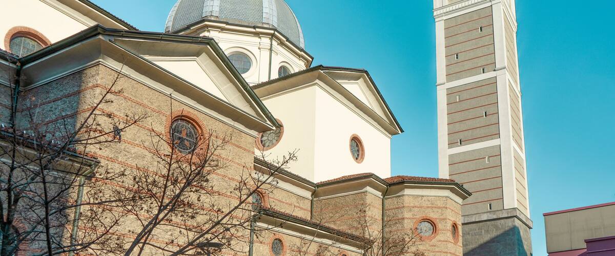 A church with a dome and a clock tower against a clear blue sky.