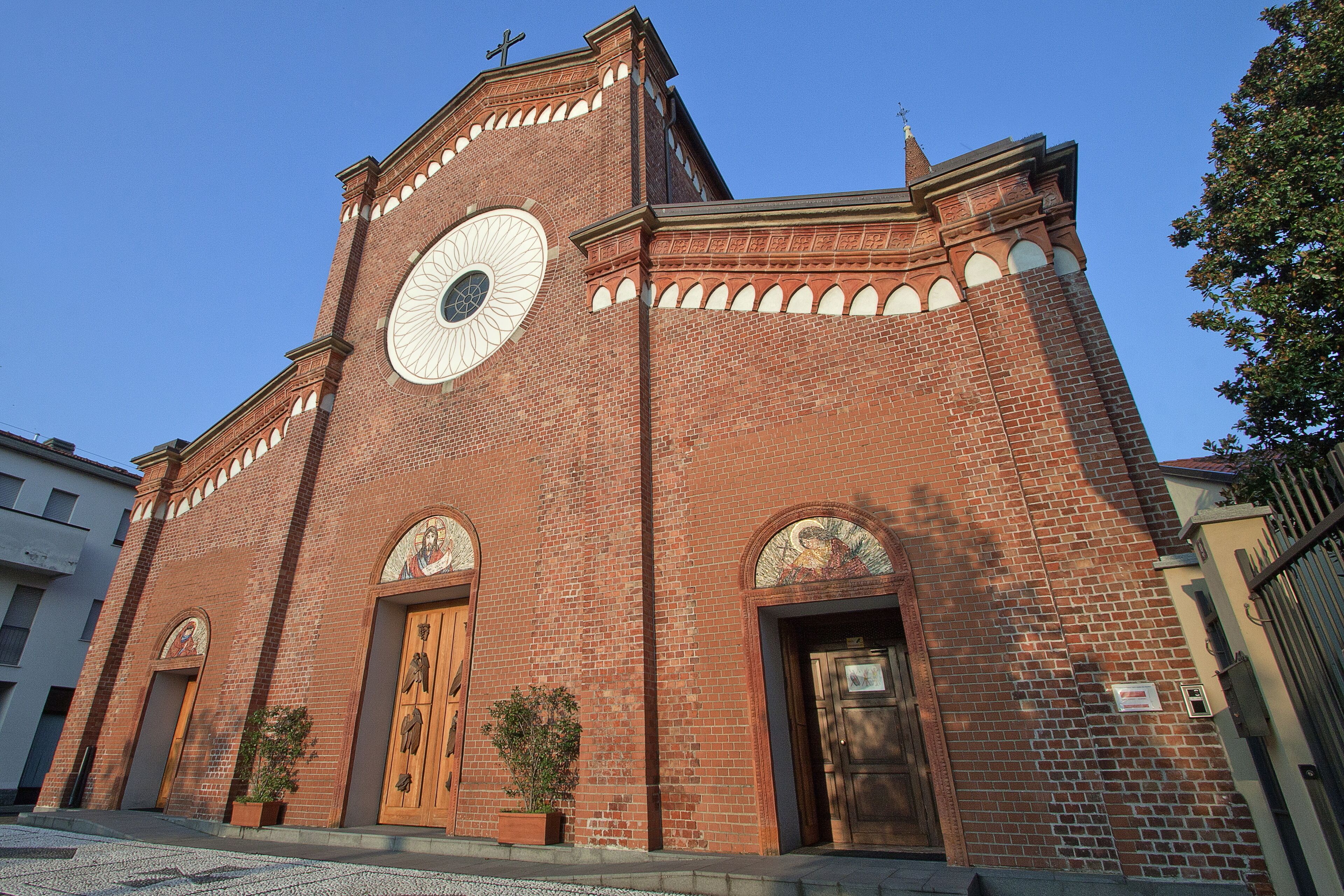 A red brick church with a large circular window and arched doorways.