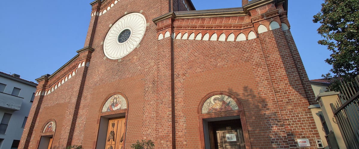 A red brick church with a large circular window and arched doorways.