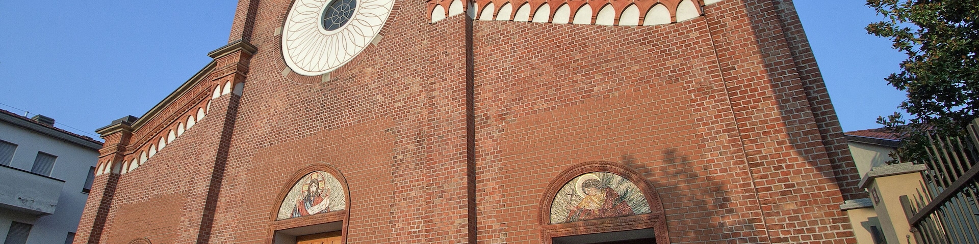 A red brick church with a large circular window and arched doorways.