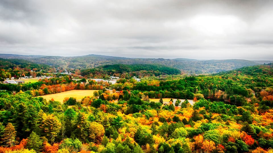A valley with autumn foliage, a river, and distant hills.