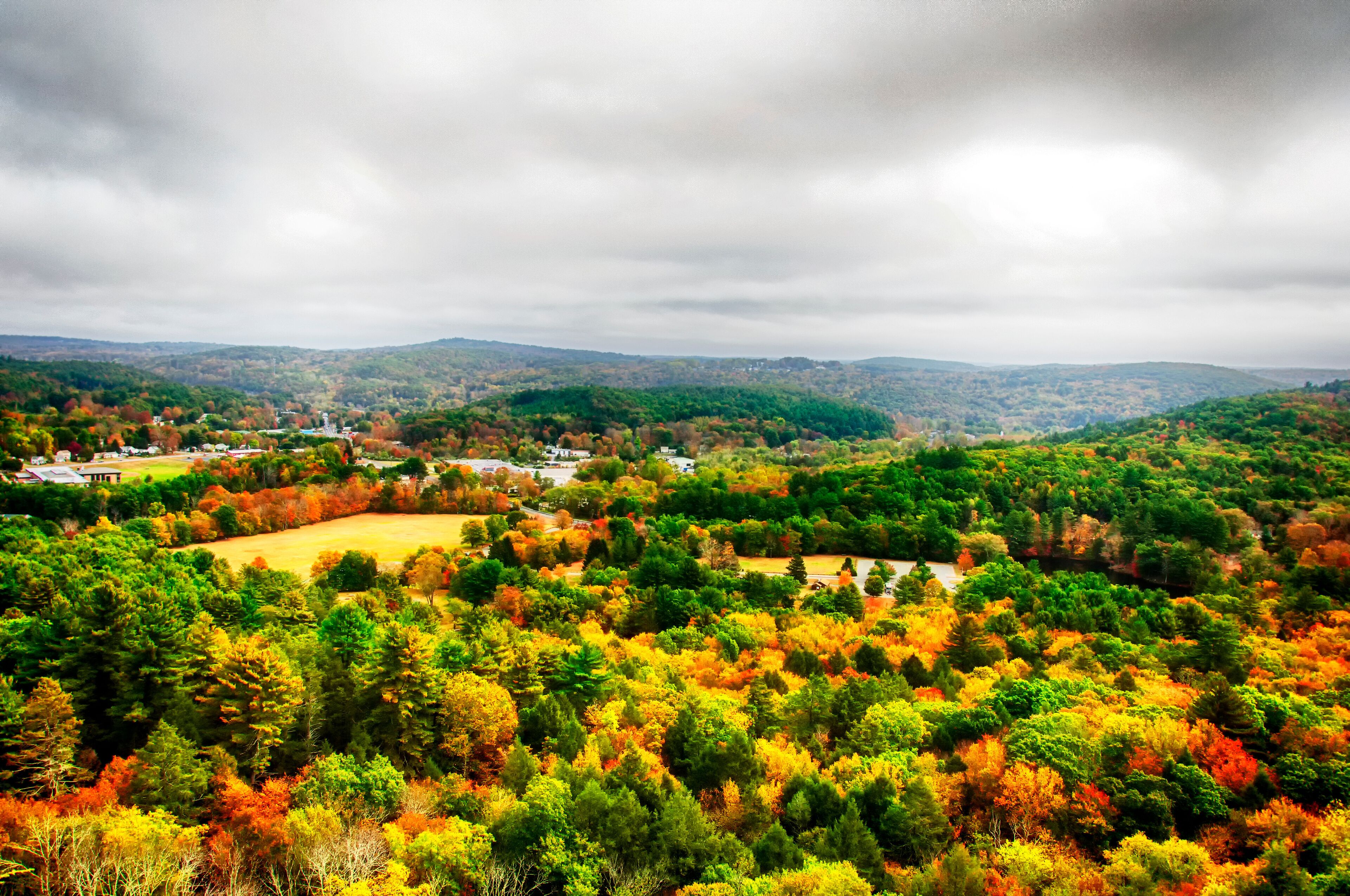 A valley with autumn foliage, a river, and distant hills.