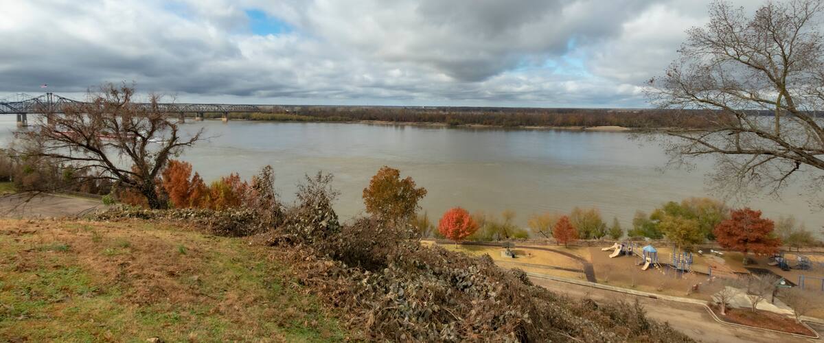 A river with a bridge, autumn trees, and a playground.