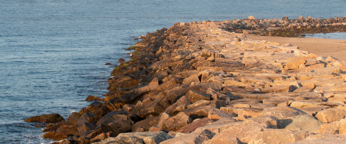 A rocky shoreline with large boulders and a sandy beach.