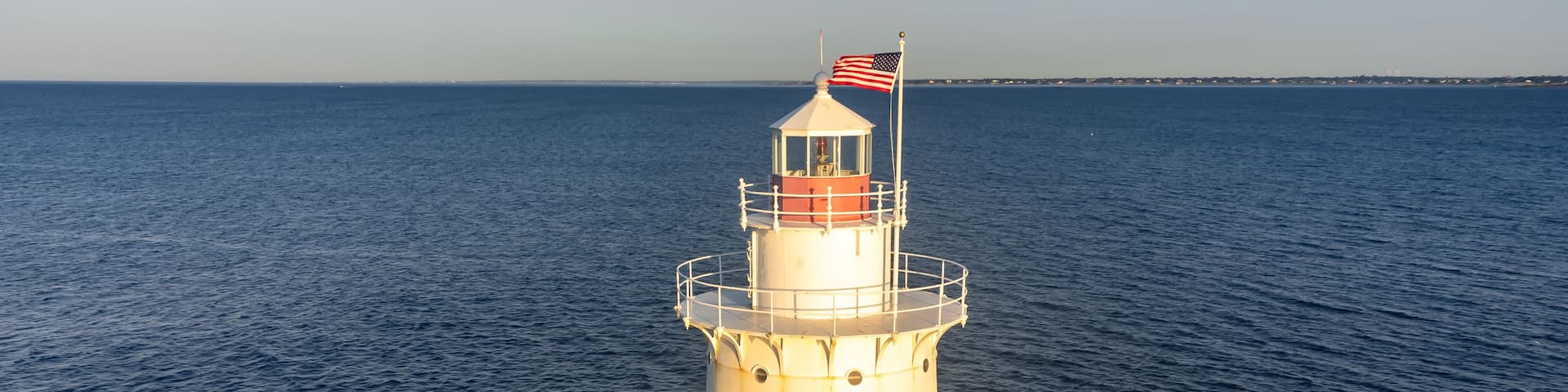 A lighthouse on a rocky outcrop with the ocean in the background.