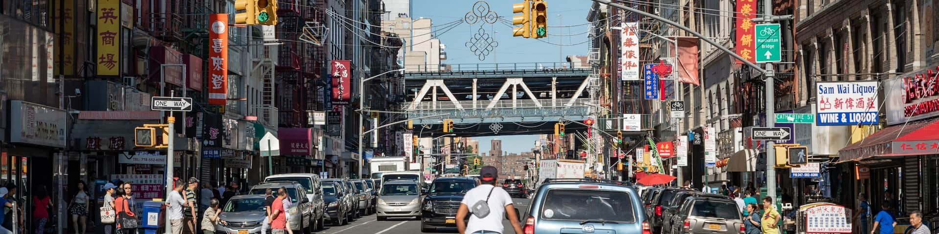 A busy urban street with cars, a cyclist, and pedestrians.