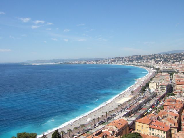 Una ciudad costera con una playa extensa, mar azul cristalino y edificios históricos a lo largo de la costa.