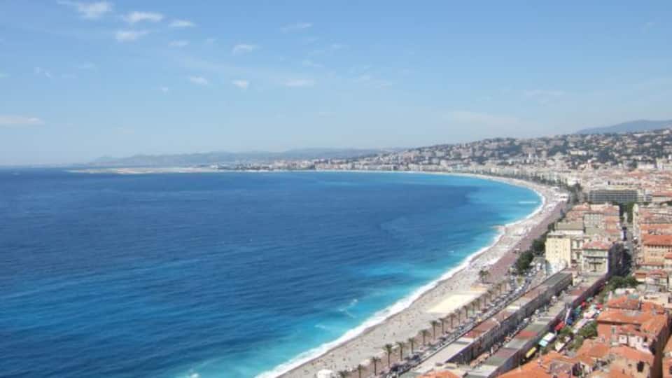 Una ciutat costanera amb una llarga platja, mar blava cristal·lina i edificis històrics al costat de la riba.
