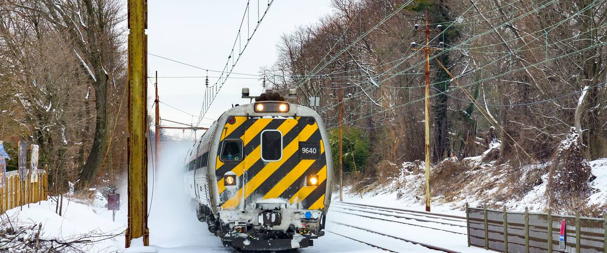 A train on tracks with snow on the ground and trees in the background.