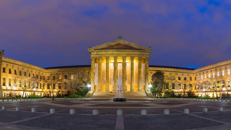 A grand neoclassical building with a central fountain, surrounded by a symmetrical plaza with bollards.