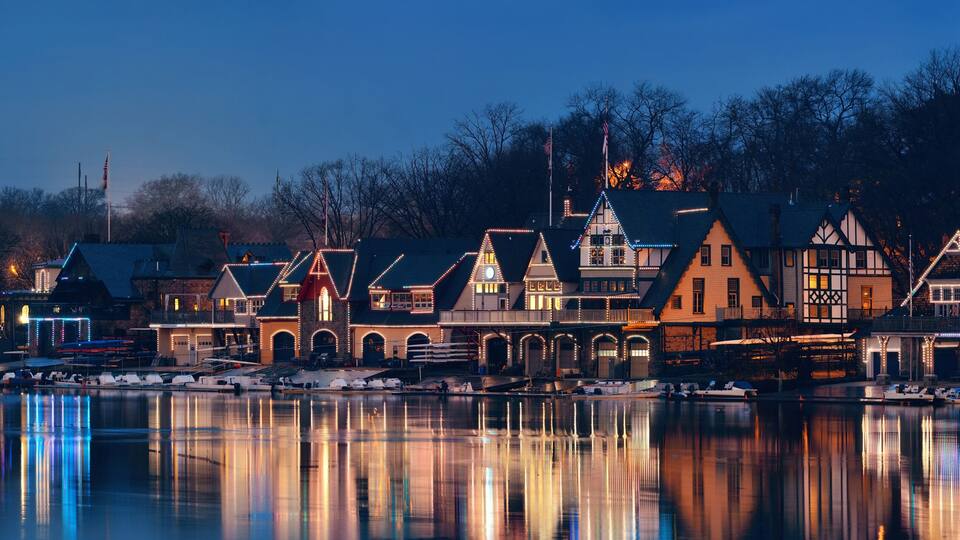 A waterfront town with historic buildings and a calm lake reflecting the lights.