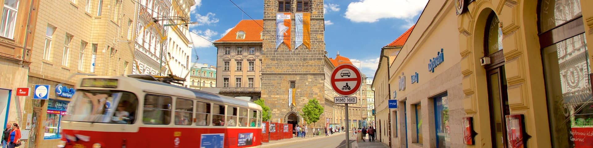 A tram on a street with historic buildings and a church tower in the background.