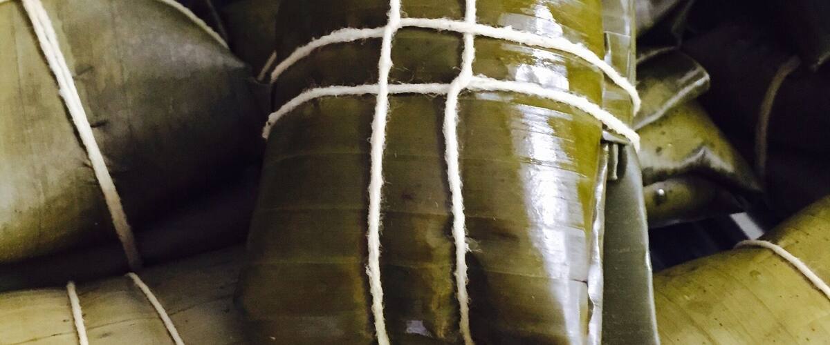 A collection of food items wrapped in leaves, tied with strings.