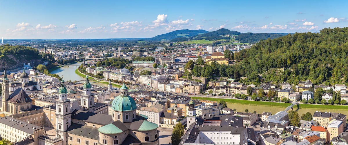 A panoramic view of a city with a river, historic buildings, and a bridge.