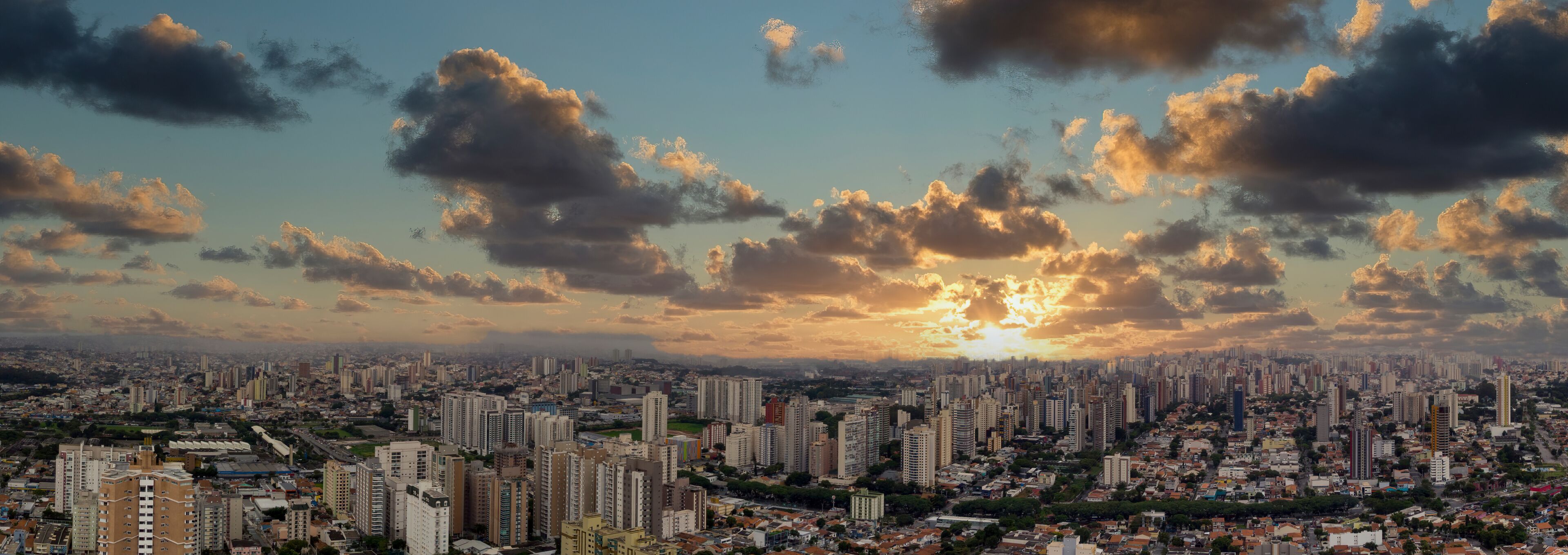 A cityscape with high-rise buildings and a sunset sky.