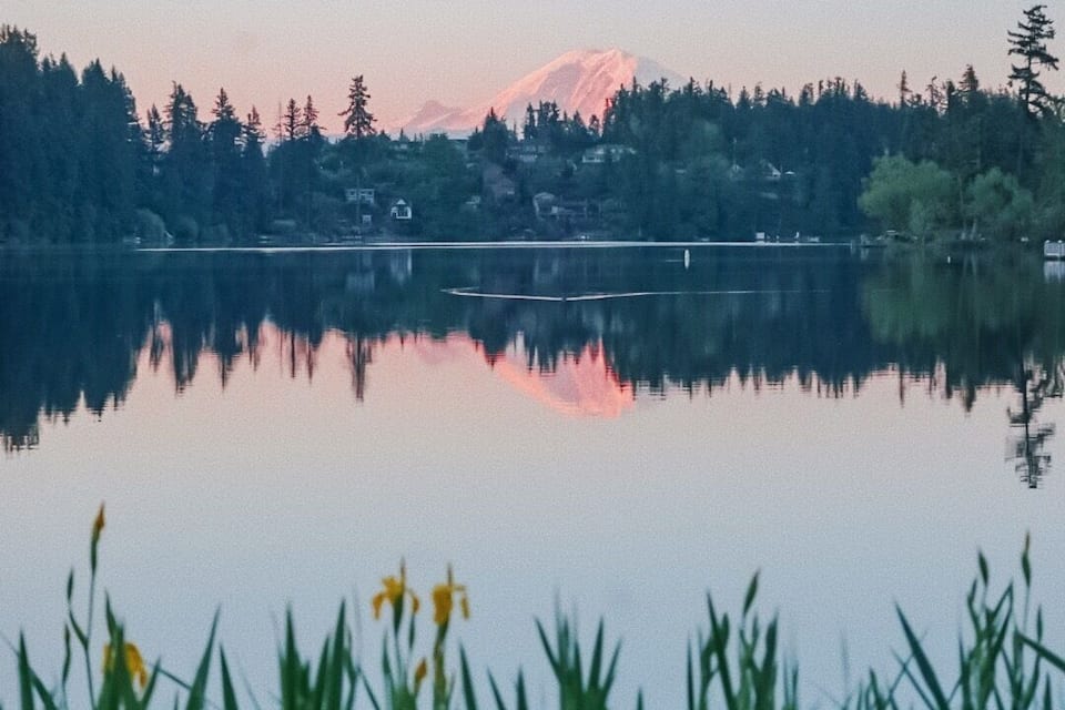 A calm lake with a mountain in the background and a forested shoreline.