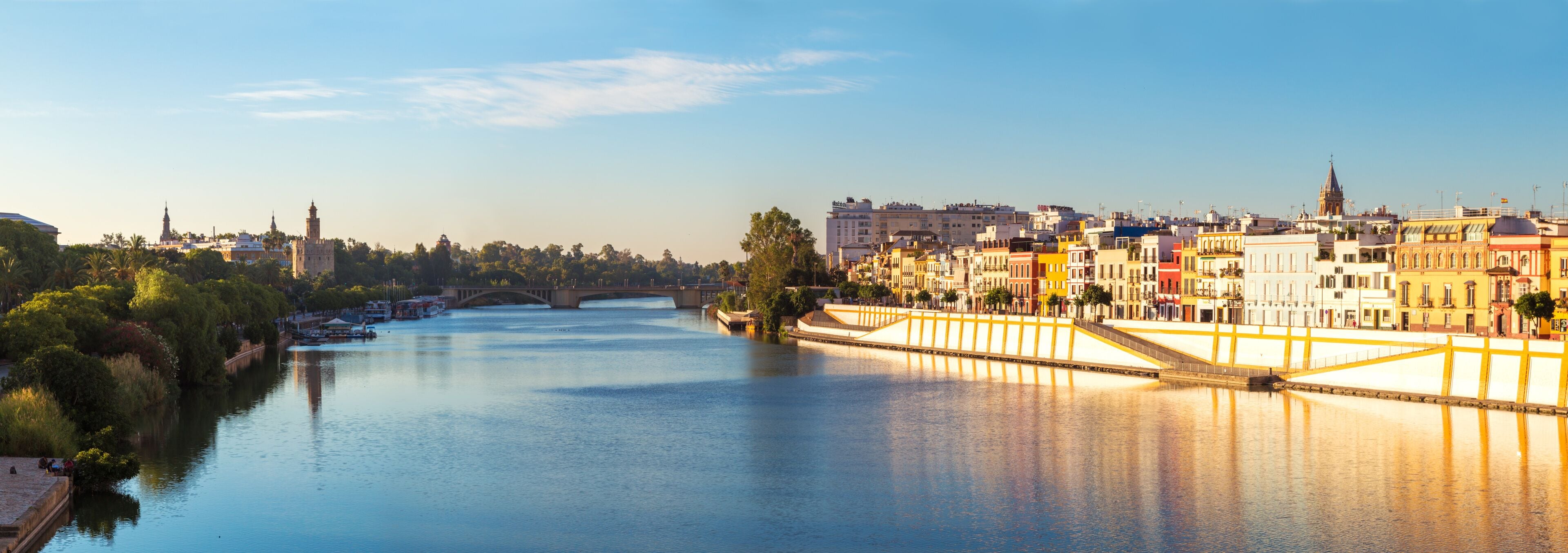 A river with a bridge, buildings, and a tower in the background.