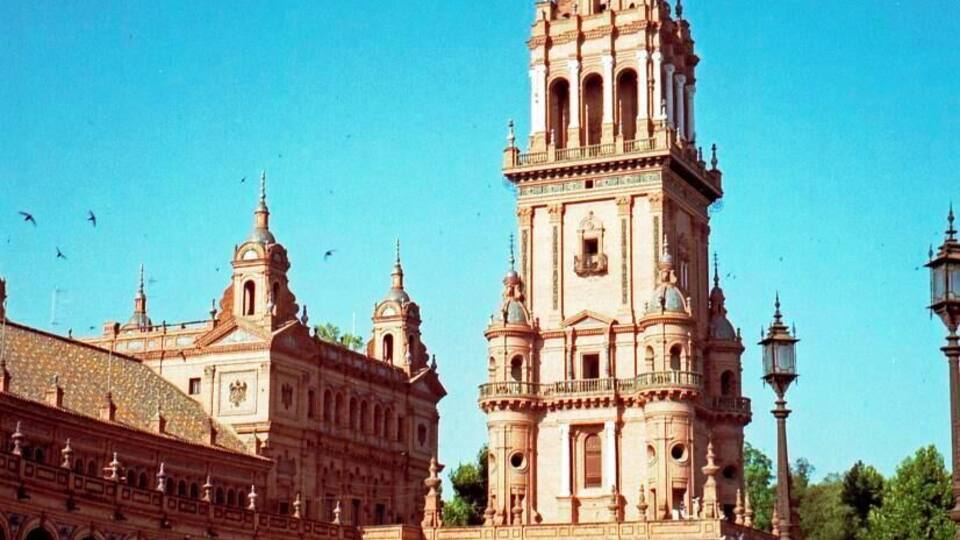 A historic building with a prominent tower and arched walkways.