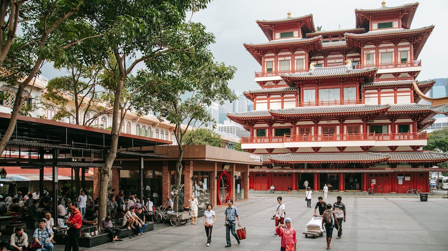 A traditional multi-tiered building with red and white colors, surrounded by trees and people.