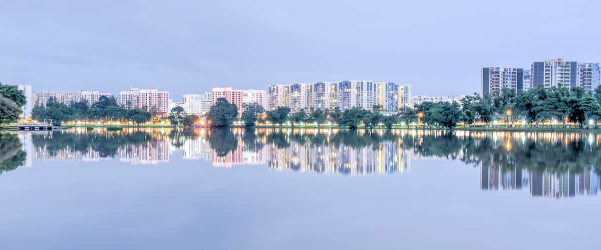 A calm lake reflecting high-rise buildings and trees.