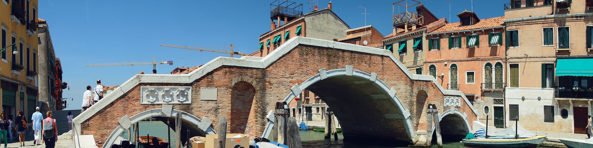 Um canal com barcos, uma ponte e edifícios históricos.