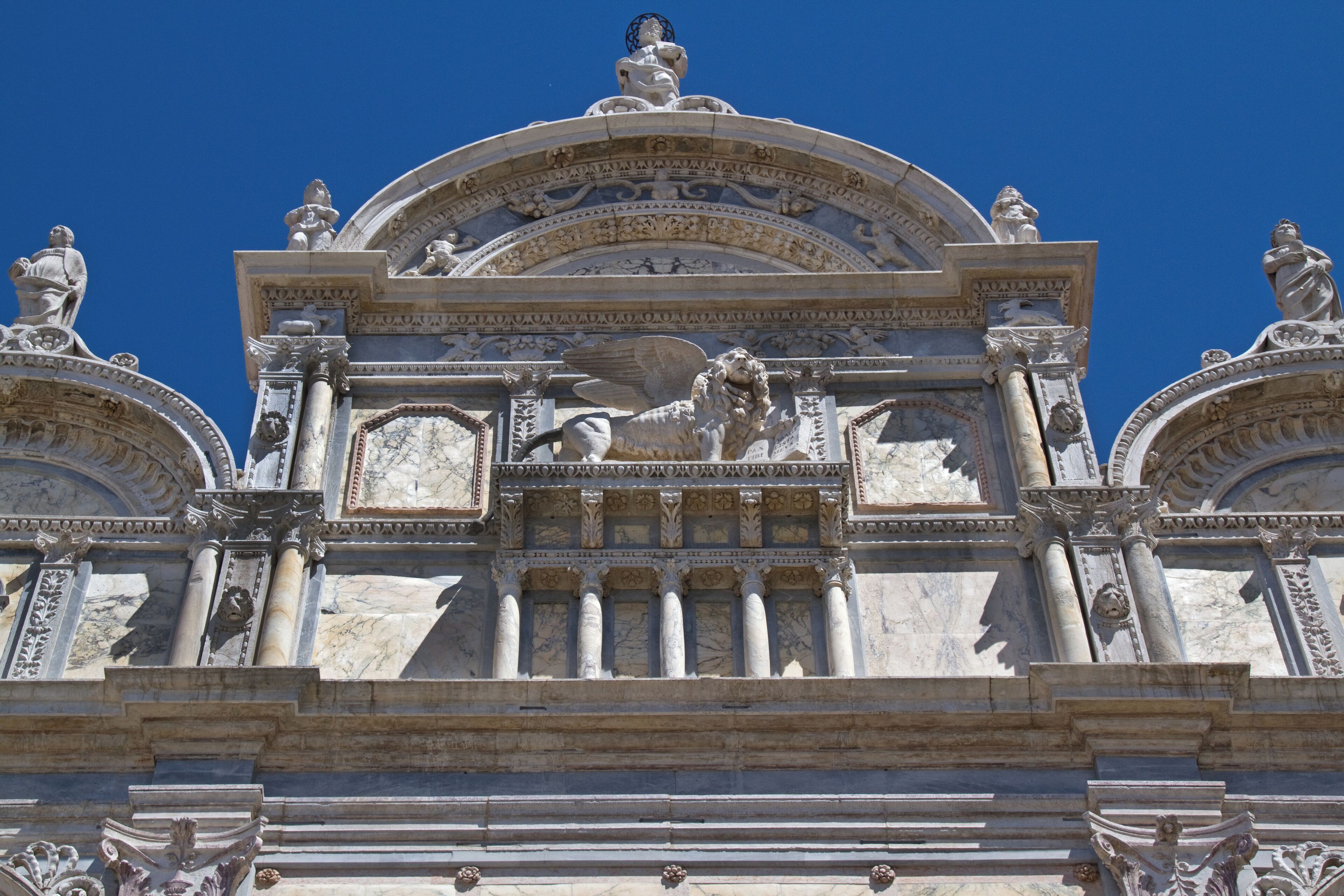 A detailed architectural facade with statues and columns.