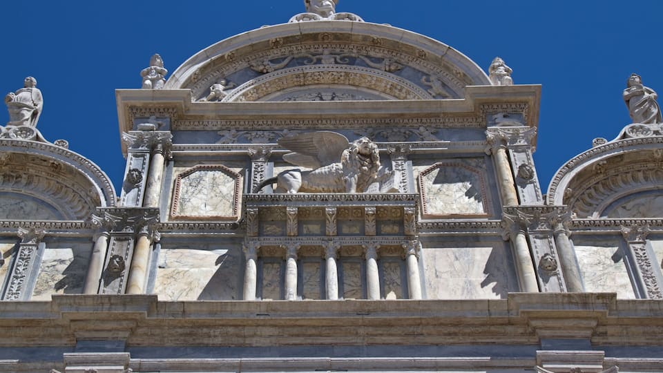 A detailed architectural facade with statues and columns.