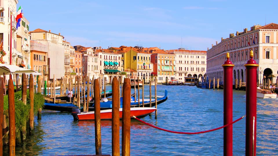 Un canale con barche, pontili in legno e edifici storici.